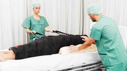Health care workers turning patient with pressure ulcer